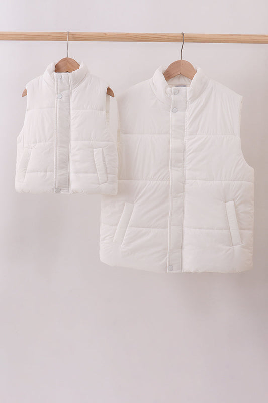 Two white puffer vests hanging on wooden hangers against a white background
